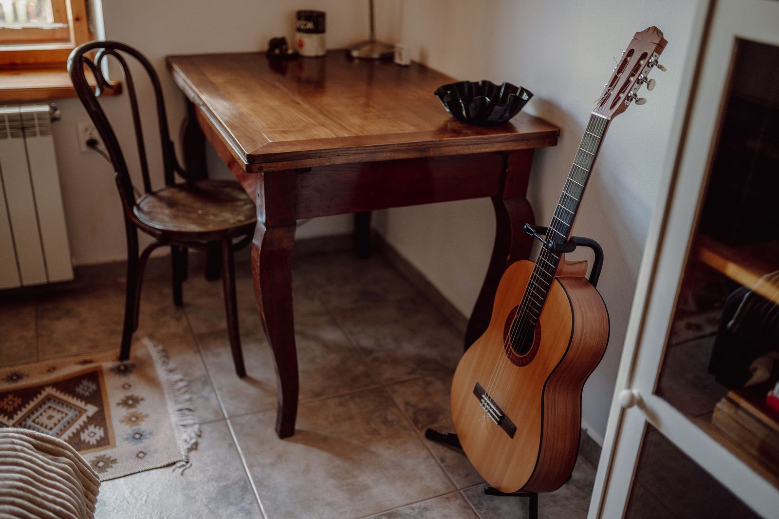 Wooden table with a wooden chair and a guitar on a stand